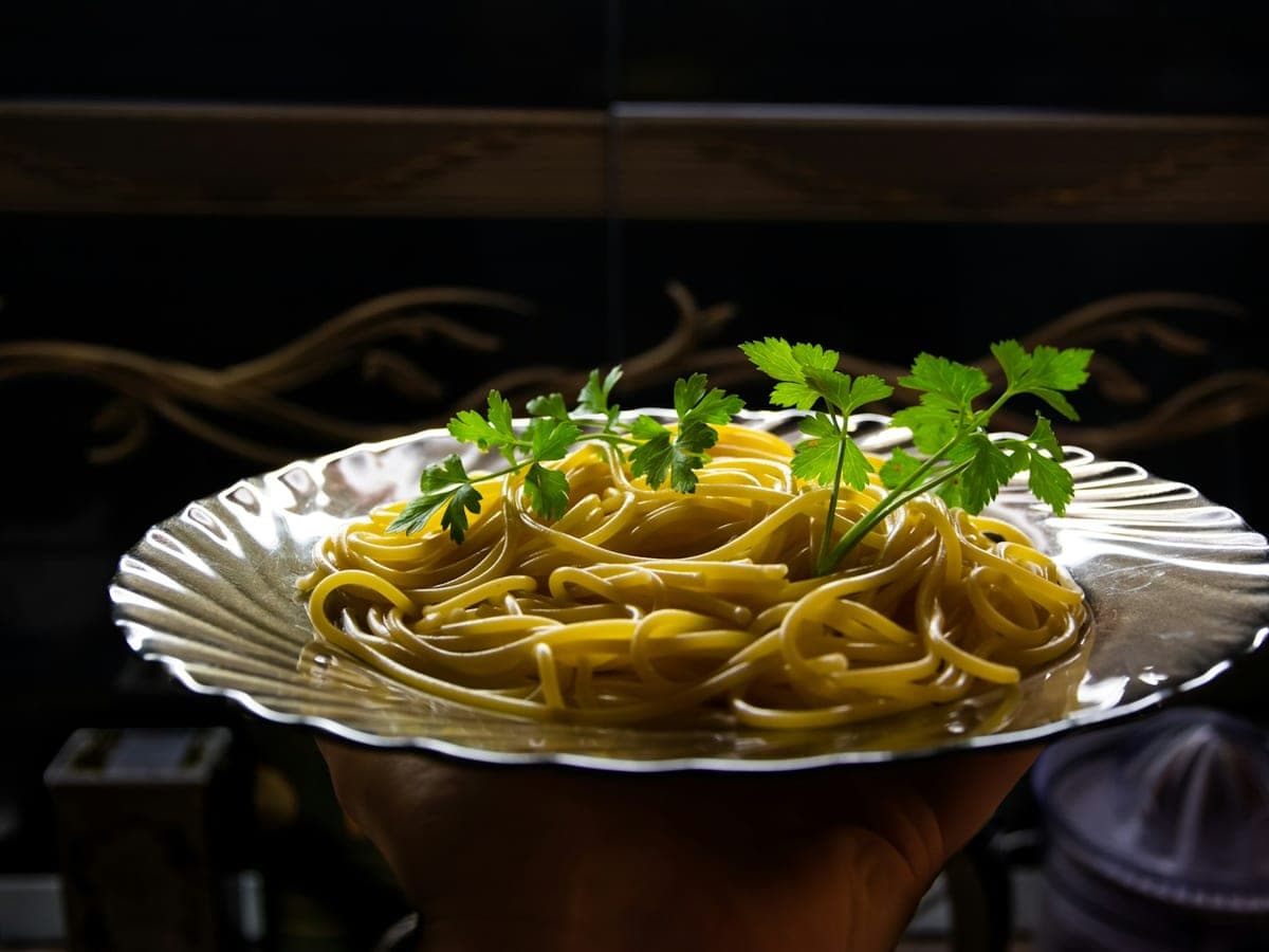 Een bord spaghetti aglio e olio met plakjes goudbruine knoflook, rode pepervlokken en gehakte peterselie.
